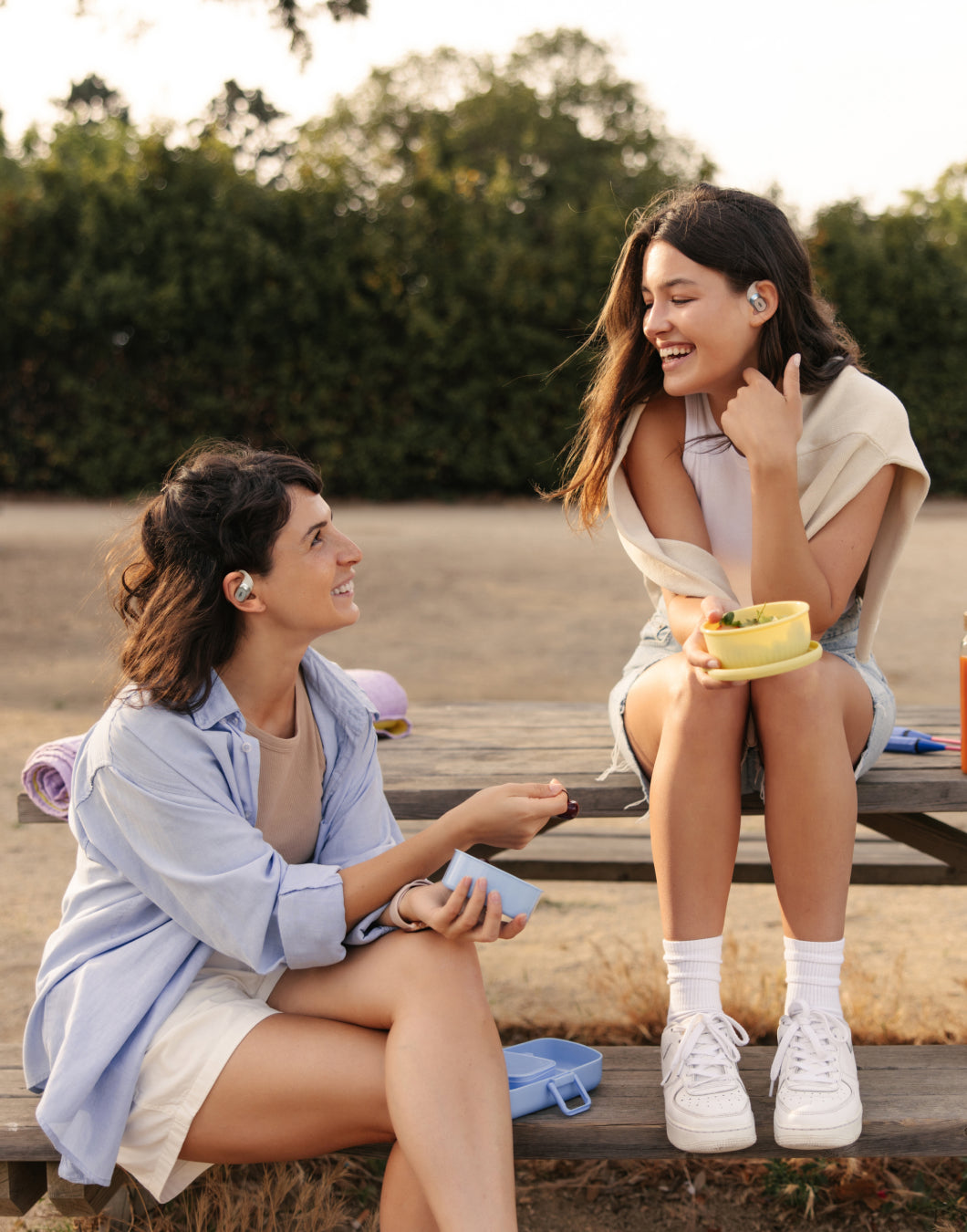 two women talk with open earbuds